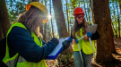 Two women take forest measurements.