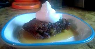 picture of a cooked pudding with whipped cream and sauce in a small plate