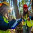 Two women take forest measurements.